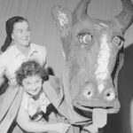 Hutt Kindergarten Mother's Variety Show, with milkmaid and two women being legs for papier mache cow. Lower Hutt. Negatives of the Evening Post newspaper. Ref EP/1959/3813--F Alexander Turnball Library, Wellington, New Zealand